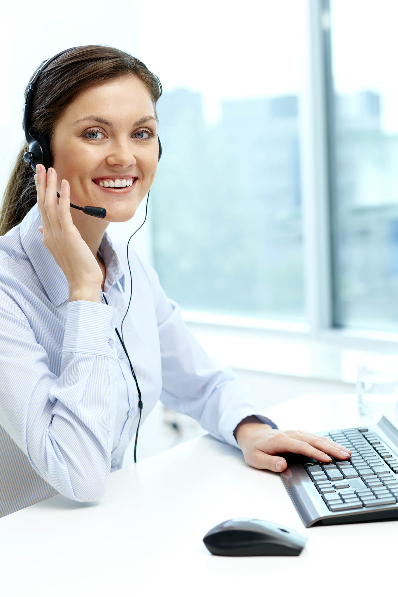 Portrait of young operator with headset looking at camera with friendly smile